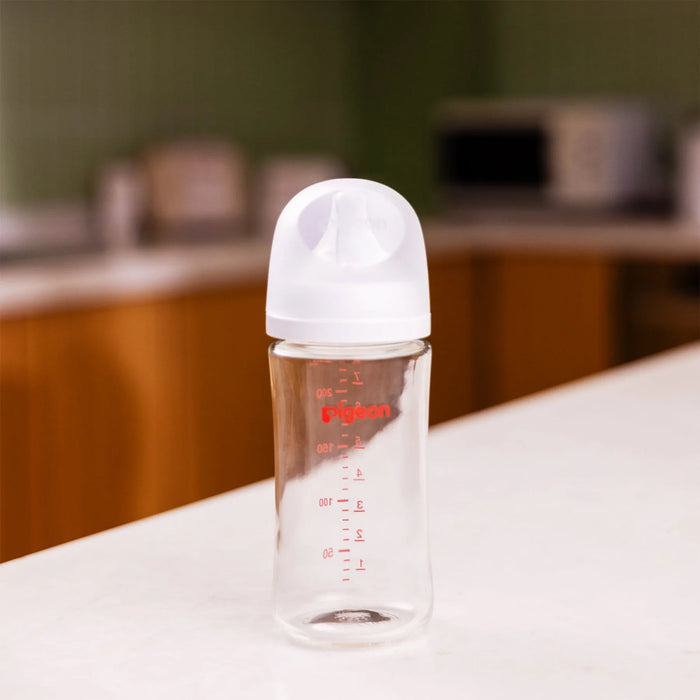 Clear glass baby bottle with white cap on a table in an indoor setting