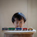 child plays with set of five wooden toy cars