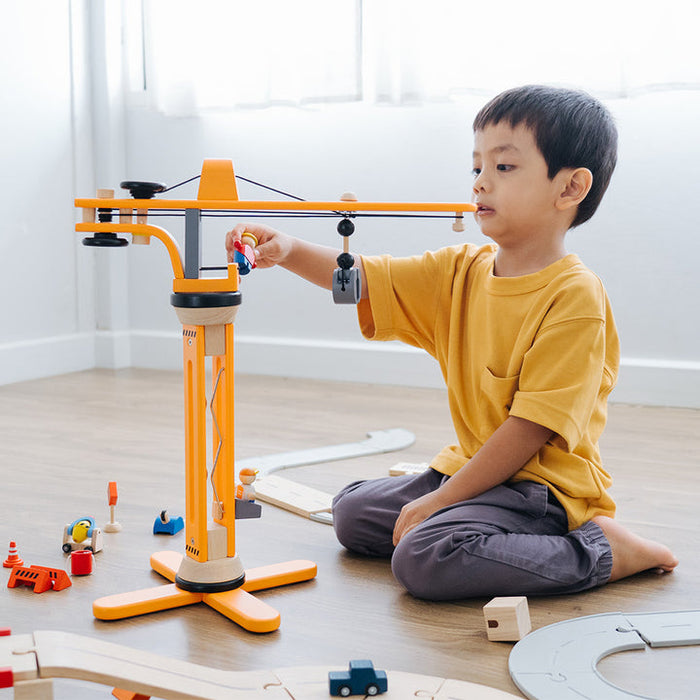 Child playing with a toy construction set on a wooden floor.