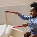 Child playing with a wooden toy hammer and anvil set indoors.