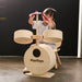 Child playing with a wooden drum set labeled 'PlanToys' against a dark background