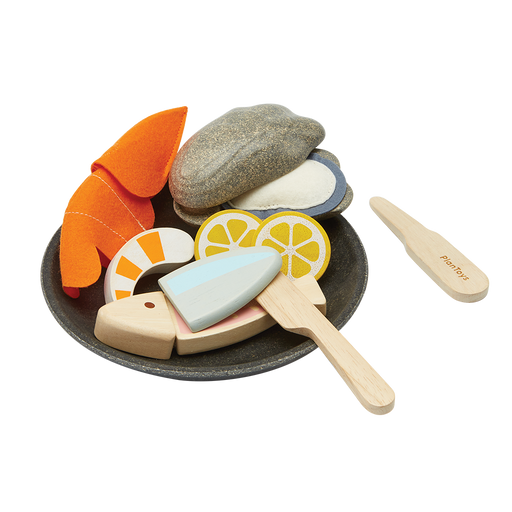 Set of toy food items including fish, lemon slices, and a knife on a white background