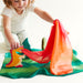 Child playing with colorful play scene of toys set on playsilks on a white background
