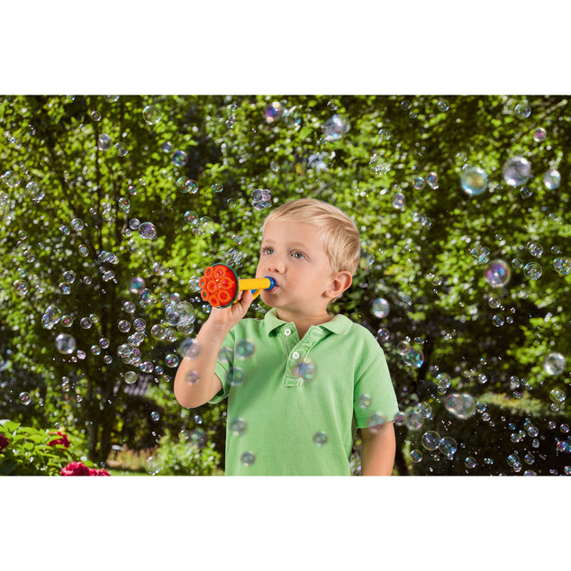 Child plays outdoors by blowing bubbles out of the Multi Bubble Trumpet Toy