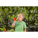 Child plays outdoors by blowing bubbles out of the Multi Bubble Trumpet Toy