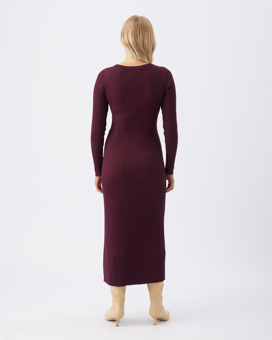 Woman wearing a burgundy ribbed dress on a white background