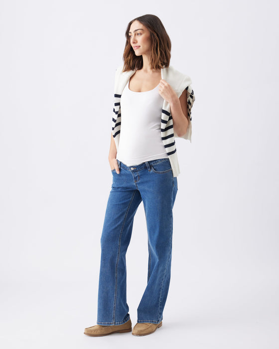 Maternity jeans on pregnant model with white fitted tee and striped sweater draped over her shoulders