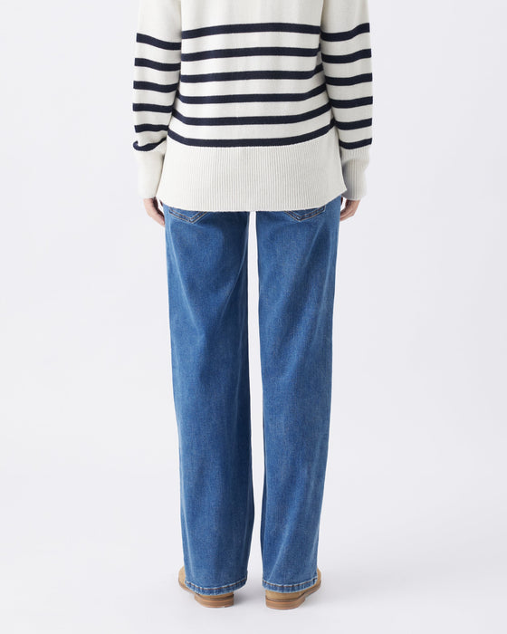 a woman stands with her back facing the camera on a white background and detail of jean style at back of legs is shown