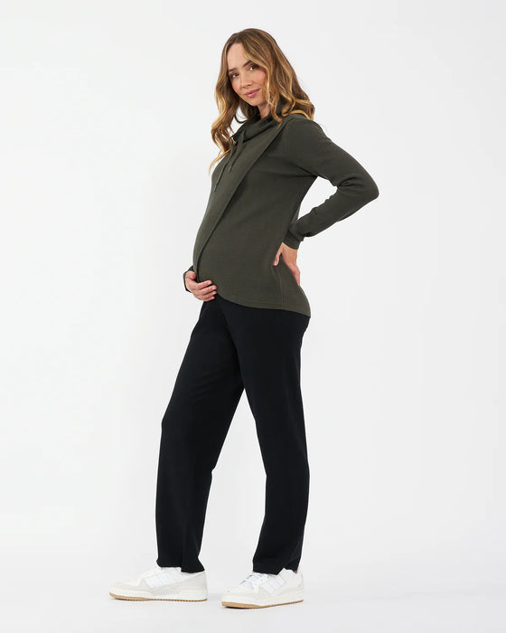 Woman wearing a green top and black pants on a white background