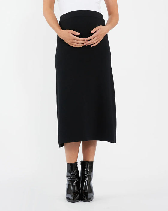 Person wearing a black skirt and black boots on a white background