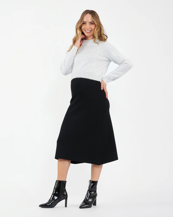 Woman wearing a white sweater and black skirt on a white background