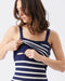 Woman wearing a navy and white striped tank top on a plain background