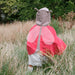 Child wearing a ladybug costume standing in a grassy field with trees in the background