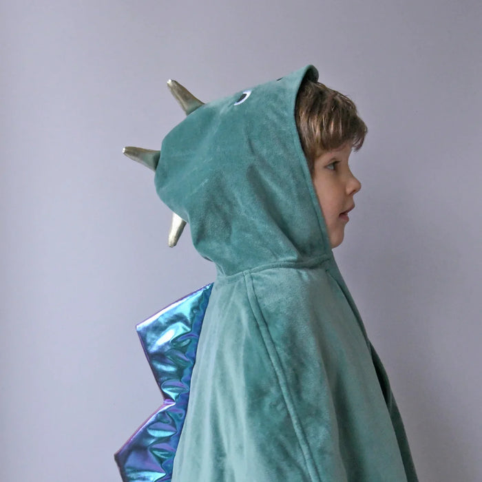 Child wearing a teal dinosaur costume with a hood and spikes on a plain background