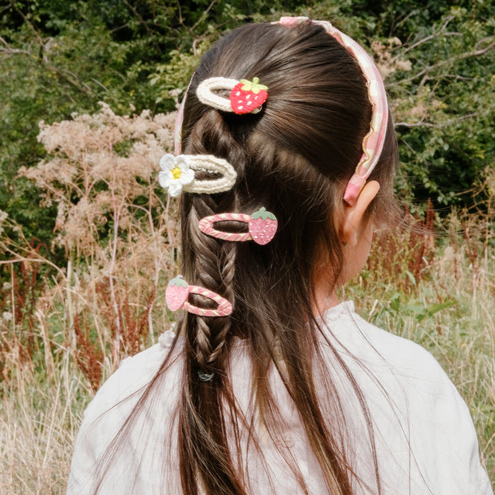 Person with braided hair wearing decorative hair clips in a natural setting