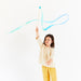 Child holding a blue ribbon on a wooden streamer wand against a white background