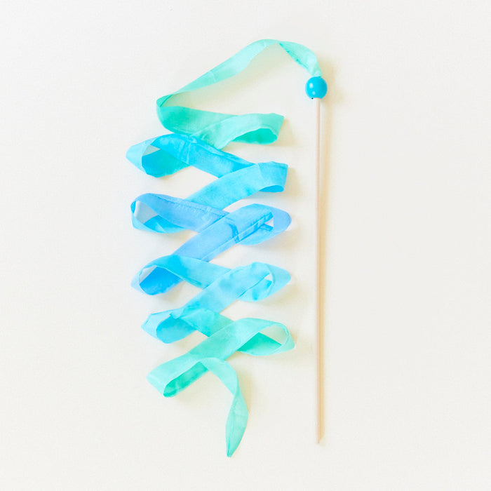 Blue and green silk ribbon on a wooden wand against a white background