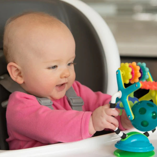 child sitting in highchair playing with teething toy