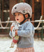 Child wearing a scoot n ride helmet and holding a toy in an outdoor setting