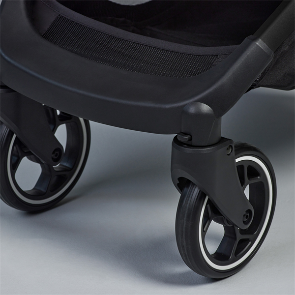 Close-up of a black stroller wheel on a gray background
