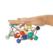 Colorful geometric wooden toy compresses by a hand on a white background