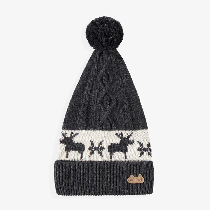 Dark gray knit beanie with a pom-pom and reindeer pattern on a light gray background