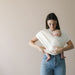 Woman holding a baby in a white wrap against a beige background