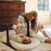 Woman interacting with a baby on a lounger with toy arch in a home setting