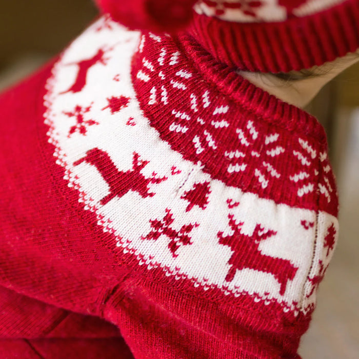 Red knitted sweater with white reindeer pattern on a blurred background
