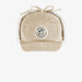 Beige corduroy cap with ear flaps tied up on top of hat on white background