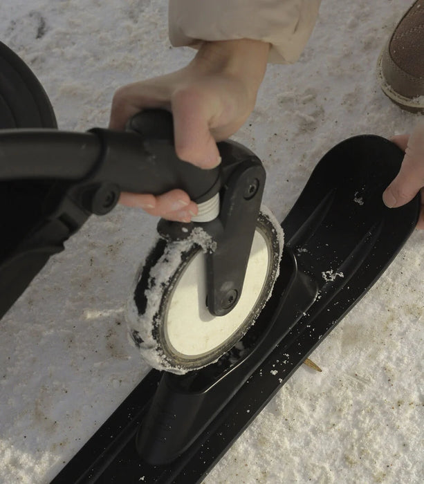 Person putting a ski set on a yoyo stroller