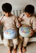 Two children playing with colorful drums indoors.
