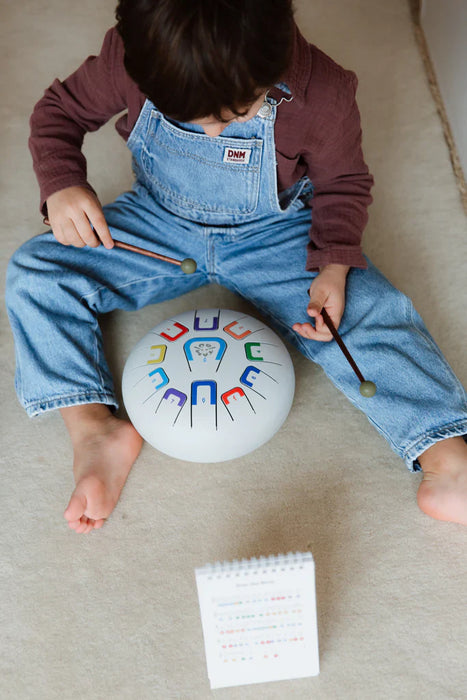 Child playing with a colorful lettered drum on a carpeted floor