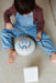 Child playing with a colorful lettered drum on a carpeted floor