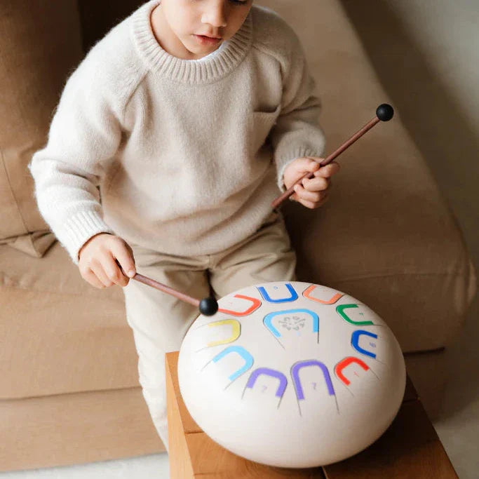 Child playing with a colorful drum on a couch