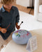 Child playing with a colorful drum and music notation card on a table.