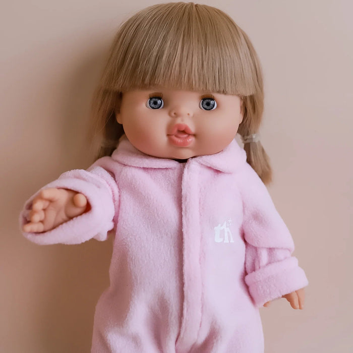 Doll wearing a pink outfit with a small white logo on a beige background