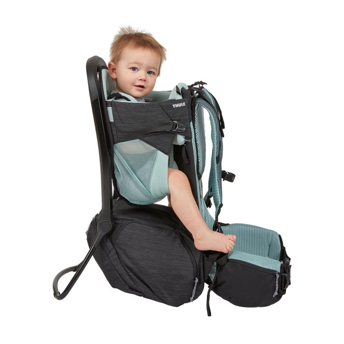 Child in a black and gray backpack carrier on a white background