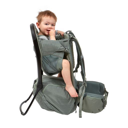 Child in a green baby carrier on a white background
