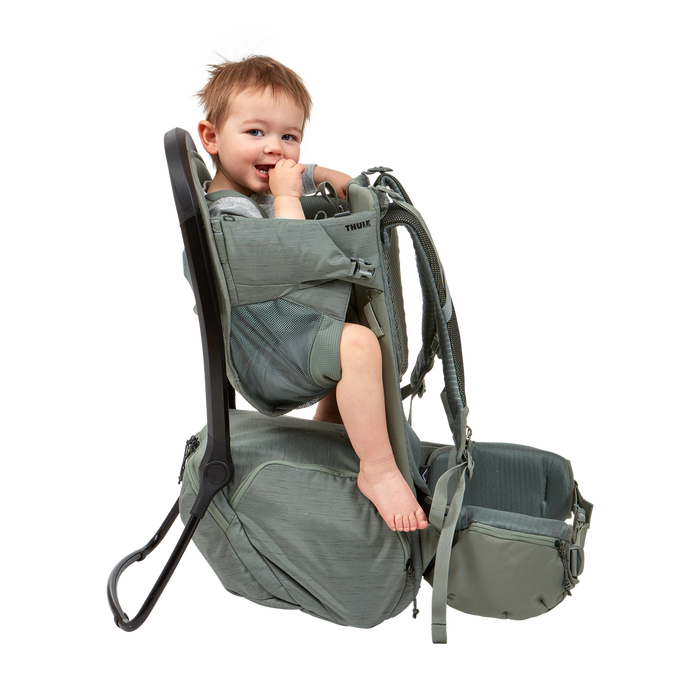 Child in a green baby carrier on a white background