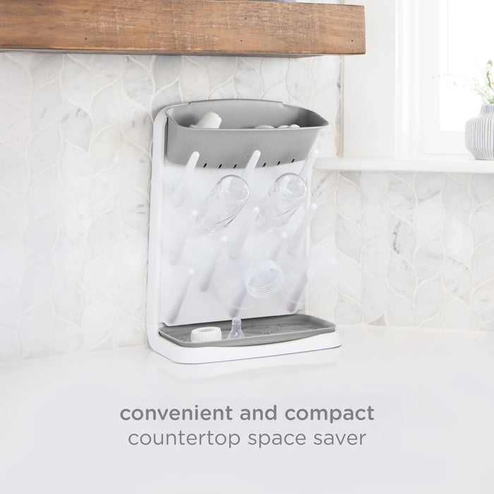 Gray countertop bottle drying rack with hanging hooks on a white marble countertop.