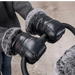 Close-up of black gloves with gray fur cuffs holding a baby stroller handle.