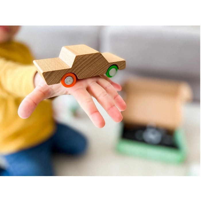 Wooden toy car on a child's hand with a blurred background