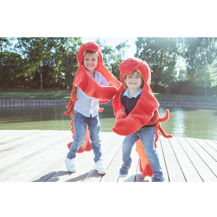 Two children in lobster costumes standing on a dock by a body of water.
