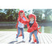 Two children in lobster costumes standing on a dock by a body of water.