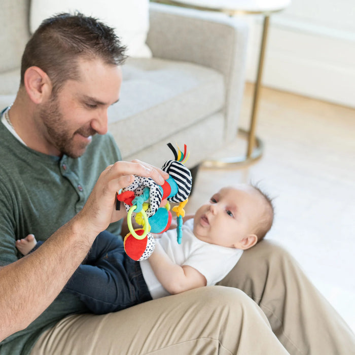 Man playing with a baby and a colorful toy in a living room setting.
