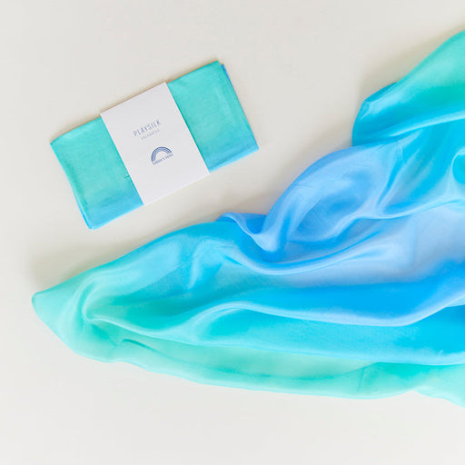 Colourful silk cloth in ocean tones against a white background