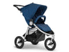 3 wheeled Bumbleride brand stroller with silver frame. Seat is in upright position with canopy extended in navy toned colour called Maritime Blue. A padded bumper bar arches over the toddler seat in the same colour fabric.