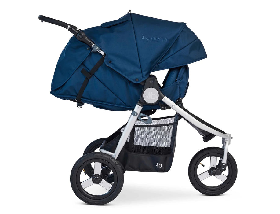 Fully reclined 3 wheeled bumbleride stroller with silver frame and maritime blue navy coloured canopy and seat. The leg rest is adjusted upward to enclose the look and feel of a bassinet. 